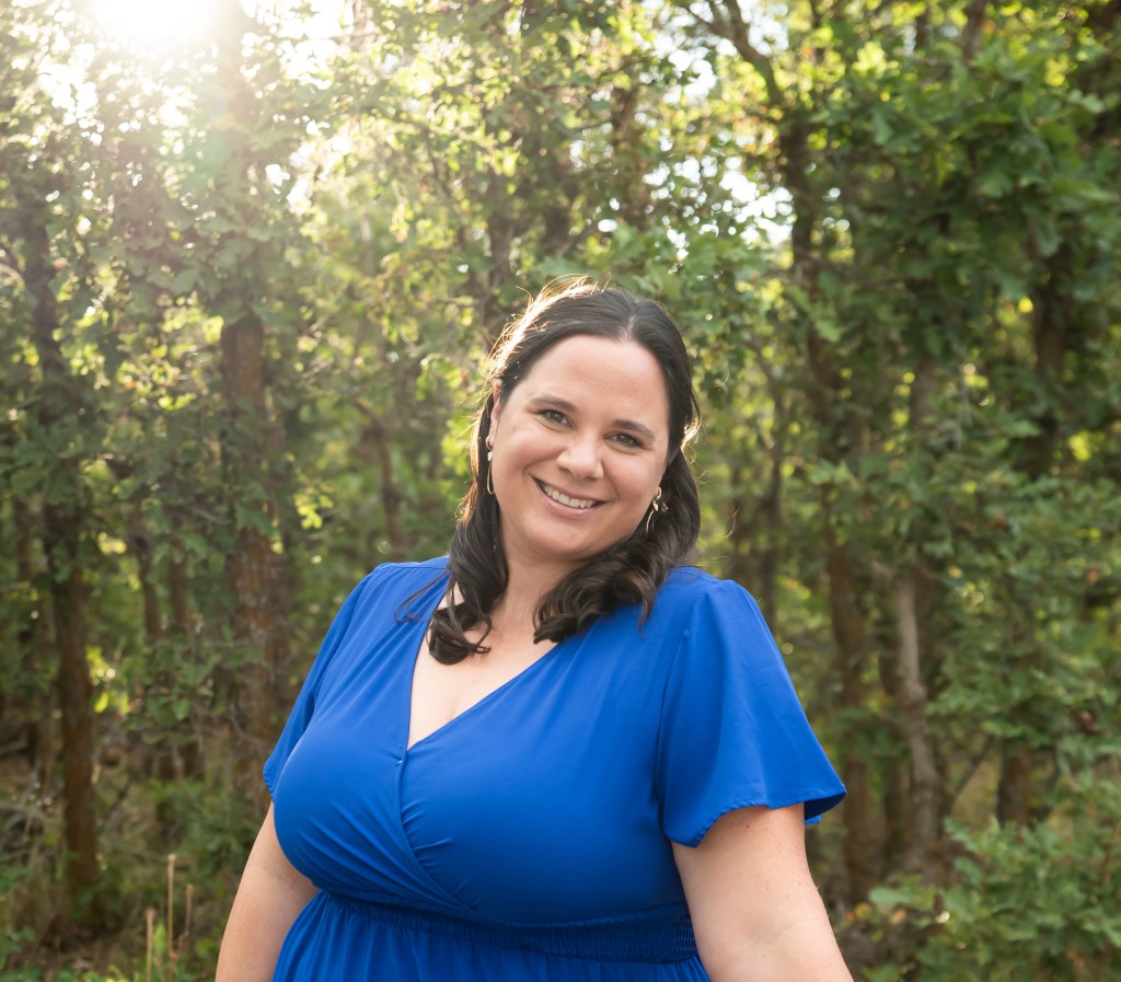 Tanja Jarvis smiling outdoors in sunlit trees